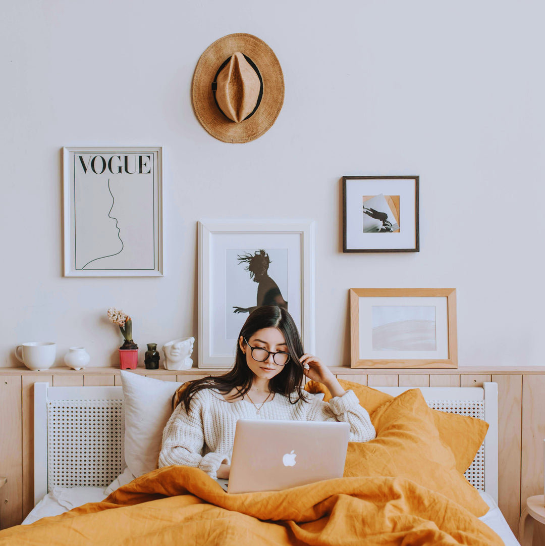 Une femme sur son ordinateur, posée dans son lit.