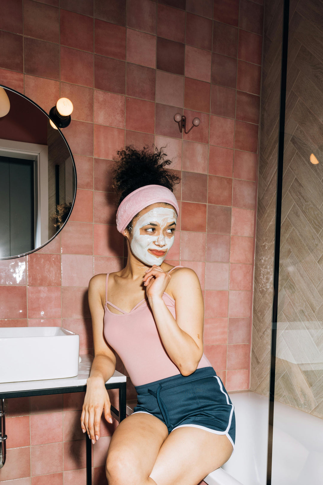 Une femme avec un masque de soins sur le visage, portant un pyjama court.